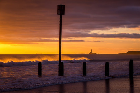 Sunrise to start the day at Blyth beach in Northumberland, with St Mary's Lighthouse in the distanceの写真素材