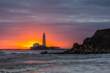 A spectacular sunrise at St Mary's Lighthouse in Whitley Bay in the North East of England, as the sky erupts in colorの写真素材