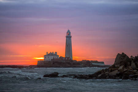 A spectacular sunrise at St Mary's Lighthouse in Whitley Bay in the North East of England, as the sky erupts in colorの写真素材
