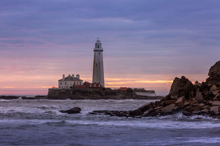A spectacular sunrise at St Mary's Lighthouse in Whitley Bay in the North East of England, as the sky erupts in colorの写真素材
