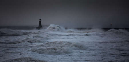 The gale force winds from Storm Arwen cause giant waves to batter the lighthouse and north pier guarding the mouth of the Tyne in Tynemouth, Englandの写真素材