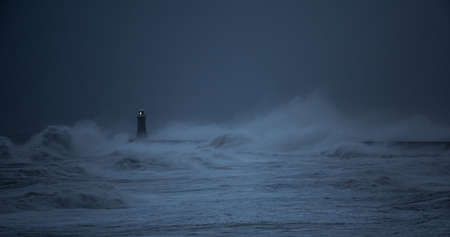 The gale force winds from Storm Arwen cause giant waves to batter the lighthouse and north pier guarding the mouth of the Tyne in Tynemouth, Englandの写真素材