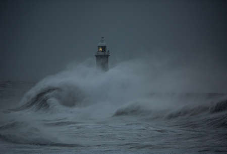 The gale force winds from Storm Arwen cause giant waves to batter the lighthouse and north pier guarding the mouth of the Tyne in Tynemouth, Englandの写真素材