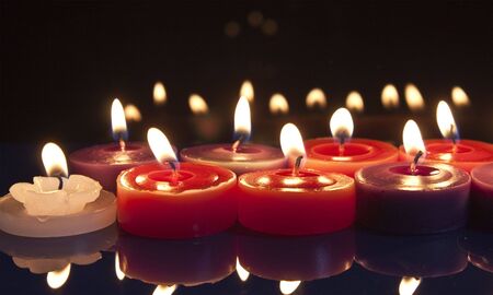 some red, white and purple candles glowing against a black backgroundの写真素材