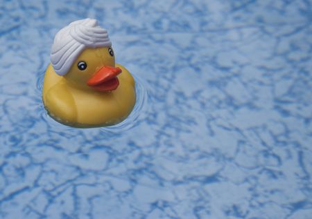 a toy yellow duck floating in the clear water of a bathの写真素材