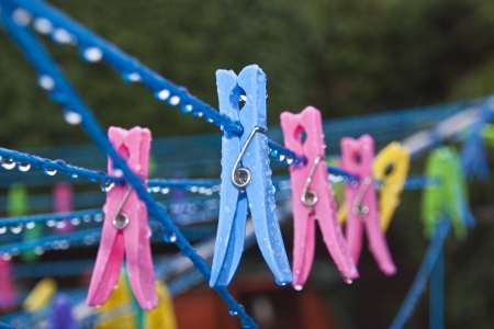 some different coloured clothes pegs on wet washing lineの写真素材