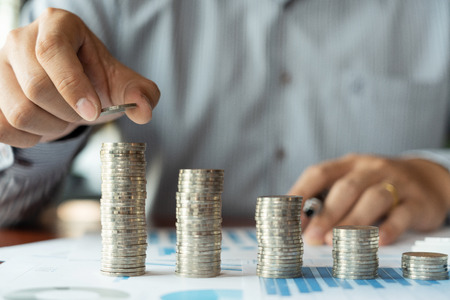 Business man hand putting coin stack for budget Saving money investment and financial accounting...