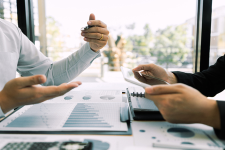 working together in office concept, young businessmen using touchpad digital tablet to discuss the situation on the market or stock yield graph chart at meeting officeの写真素材