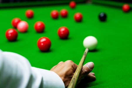 Game snooker billiards or opening frame player ready for the ball shot, athlete man kick cue on the green table in barの写真素材