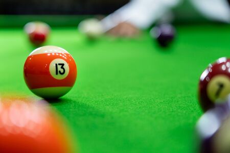 Man's hand and Cue arm playing snooker game or preparing aiming to shoot pool balls on a green billiard tableの写真素材