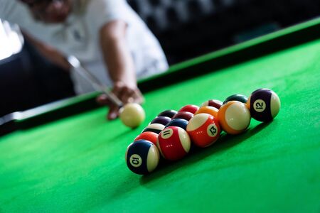 Man's hand and Cue arm playing snooker game or preparing aiming to shoot pool balls on a green...