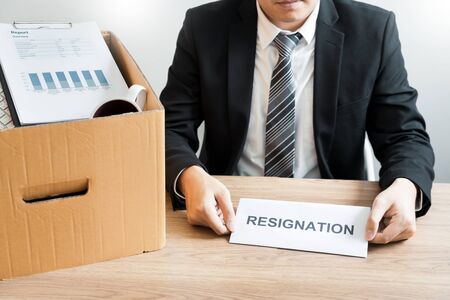 Businessperson carrying packing personal company on brown cardboard Box and resignation letters for...