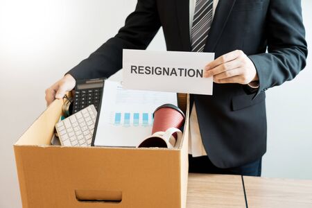 Businessperson carrying packing personal company on brown cardboard Box and resignation letters for...