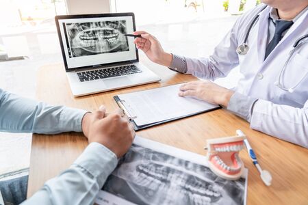 Medical team discussing, health care talking to female patient, Medical conferrence concept, doctor holding and looking at dental x-ray attending a clientの写真素材