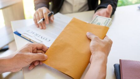 businessman receive an envelope for bribing, money corruption of their partner with both of whom are corrupt, anti bribery and corruption conceptの写真素材