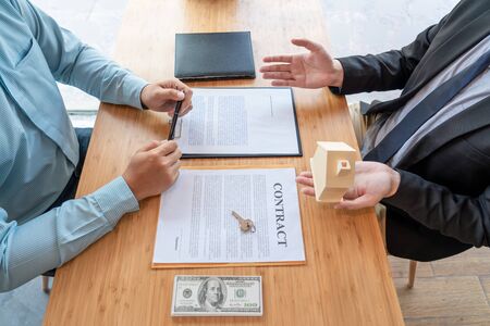 Businessman signs contract behind home architectural model Discussion with a real estate agent rental company staff  at the office property appraisal and valuation conceptの写真素材