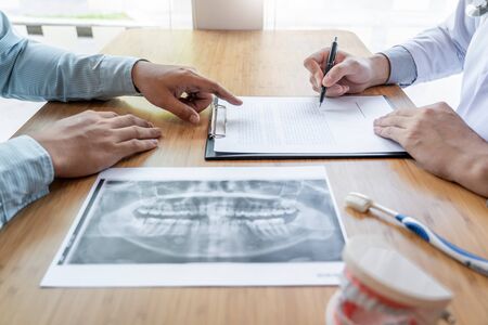 Medical team discussing, health care talking to female patient, Medical conferrence concept, doctor holding and looking at dental x-ray attending a clientの写真素材