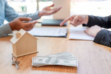 Businessman signs contract behind home architectural model Discussion with a real estate agent rental company staff  at the office property appraisal and valuation conceptの写真素材