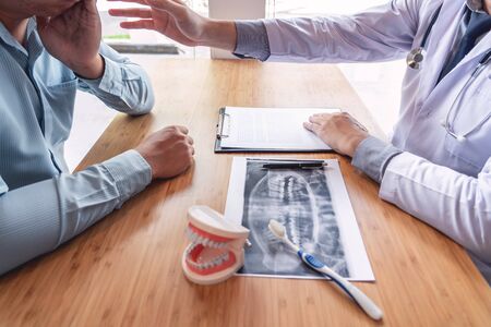 Medical team discussing, health care talking to female patient, Medical conferrence concept, doctor holding and looking at dental x-ray attending a clientの写真素材