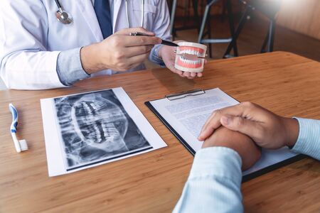 Medical team discussing, health care talking to female patient, Medical conferrence concept, doctor holding and looking at dental x-ray attending a clientの写真素材