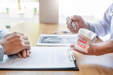 Medical team discussing, health care talking to female patient, Medical conferrence concept, doctor holding and looking at dental x-ray attending a clientの写真素材