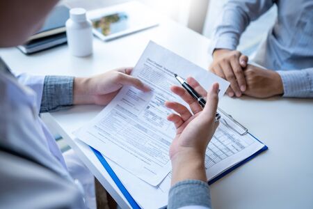 Doctor explaining and giving a consultation to a patient medical informations and diagnosis about the treatment for condition in hospital, medical ethics conceptの写真素材