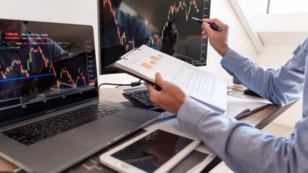 Businessman broker Analyzing finance data graphs and reports on screen for investment purposes for...