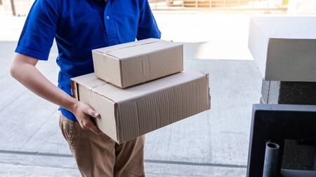 Delivery man in blue uniform handing parcel box for client  signing checklist after confirm receiving package の写真素材