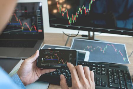 Businessman broker Analyzing finance data graphs and reports on screen for investment purposes for...