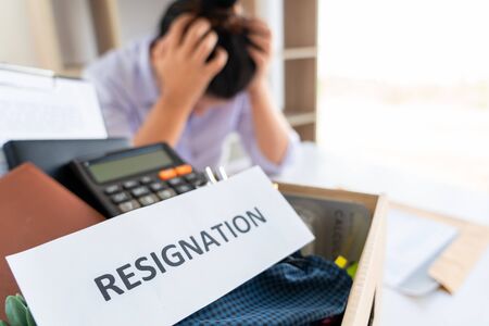 Stress of business woman packing brown cardboard box her belonging after resign and signing...