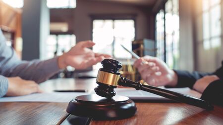 Lawyer working with client discussing contract papers with brass scale about legal legislation in...