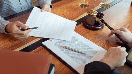 Lawyer working with client discussing contract papers with brass scale about legal legislation in...