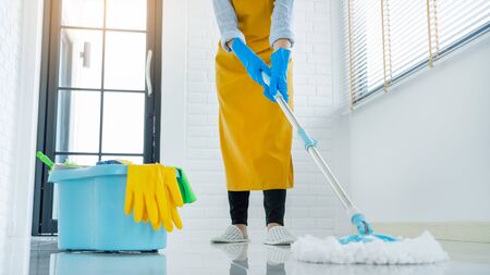 Woman housekeeper with mop and bucket with cleaning agents for cleaning floor at home, Floor care and cleaning services の写真素材