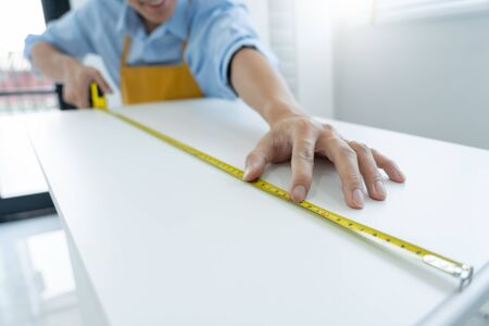 Men's hands hold a measuring tape measuring with flexible ruler for home renovation. repair, architecture and home renovation building and home conceptの写真素材