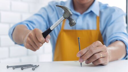 Handyman hammering a nail for House with siding panels, construction work and renovation service