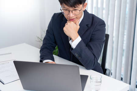 Stressed Young asian business man working late night alone in office late his eyes are gonna closing...