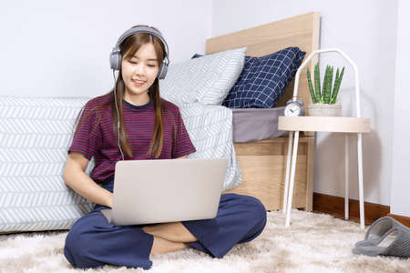Pensive asian woman is relaxing on  desktop working remotely from home with laptop for communicates...