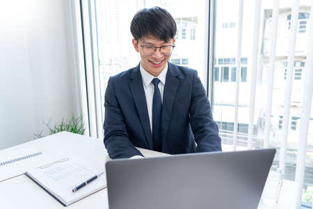 Asian man holding credit card to Online shopping with laptop computer and entering security code,...
