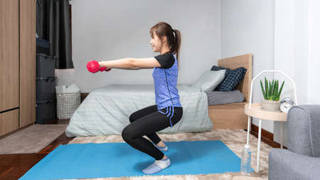 Attractive and healthy young Asian woman doing exercising at home during workout in comfy clothes on...