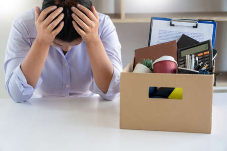 Stress of business woman packing brown cardboard box her belonging after resign and signing...
