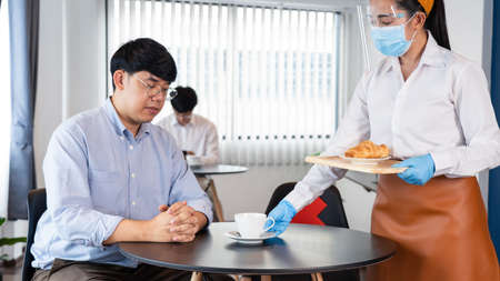 waitress wearing protective face mask and gloves for outbreak prevention Coronavirus (Covid-19)...