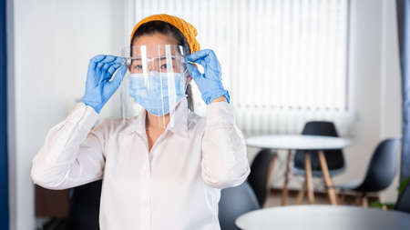 attractive asian waitress wear face mask and face shield to protection epidemic virus outbreak coronavirus disease COVID-19 in her restaurant, new normal conceptの写真素材