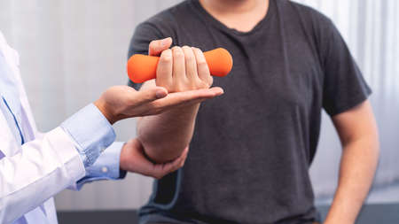 physiotherapist doctor rehabilitation consulting physiotherapy giving dumbbell exercising treatment with patient in physio clinic or hospitalの写真素材