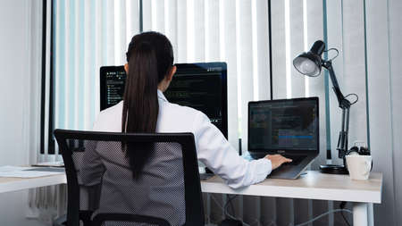Young Asian woman Programmer Typing code working with computer at table, coding cyberspace and Web Development Concept.の写真素材