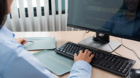 Asian woman Programming working with computer and typing data code to developing program at table In...