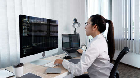 Asian Woman programmer typing source codes Programming On Computer in office, freelance web...