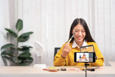 Asian woman present beauty cosmetic product and broadcast live video to social network by internet...