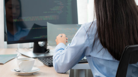 Asian woman Programming working with computer and typing data code to developing program at table In...