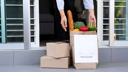 Lifestyle concept A wife house picking the bag full of the colorful vegetable delivered during her quarantine.の写真素材