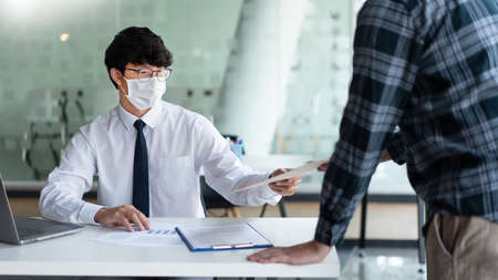 Covid-19 concept two businessmen wearing a mask planning for new project during Coronavirus outbreak (COVID-19).の写真素材